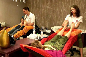 Deux femmes qui massent les pieds de deux personnes couchées